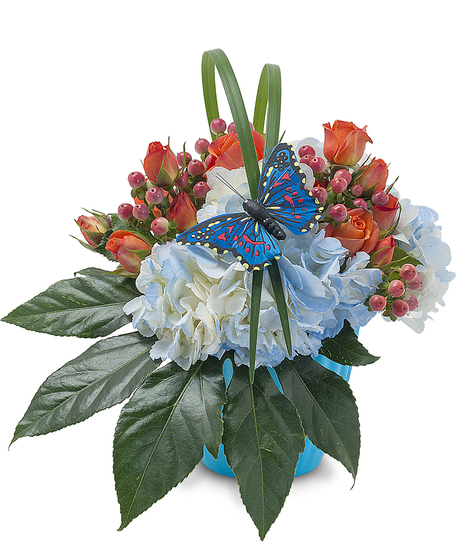 Spray roses, blue hydrangea and hypericum with foliage in a blue vase with butterfly decoration.