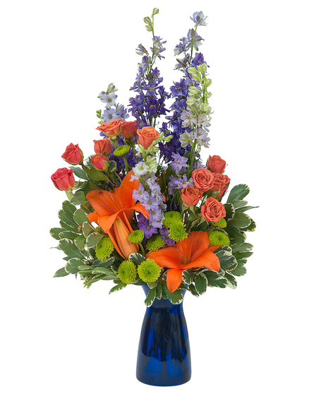 Lilies, roses, mums and larkspur in a cobalt blue bud vase.