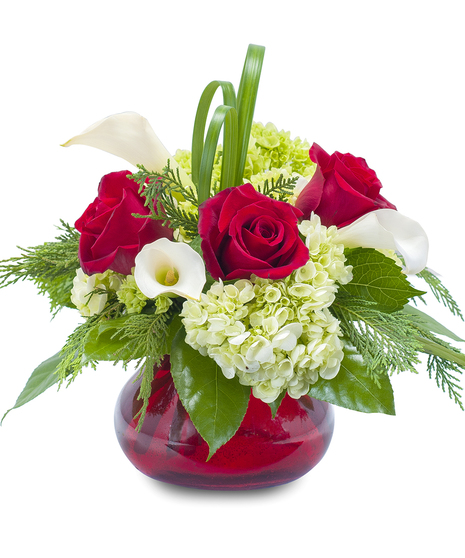 Red and white flowers and greenery in a red glass vase.