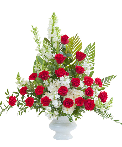 Sympathy urn of red and white flowers with lush foliage. 