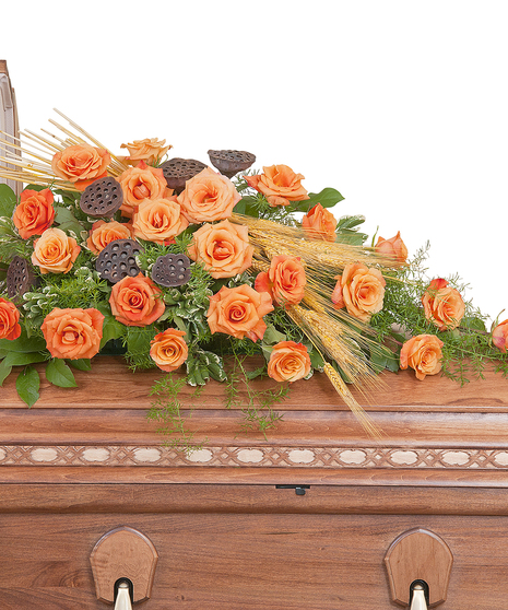 Casket spray of orange roses, wheat and pods with greenery. 