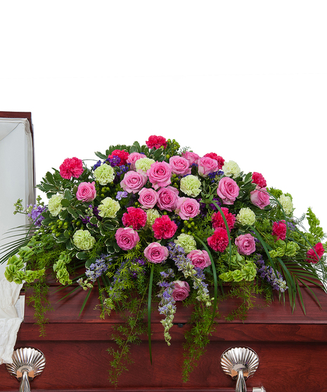 Casket spray of bright pink and purple flowers with greenery. 