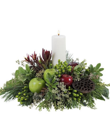 Winter centerpiece with a white pillar candle, winter greenery, apples and more