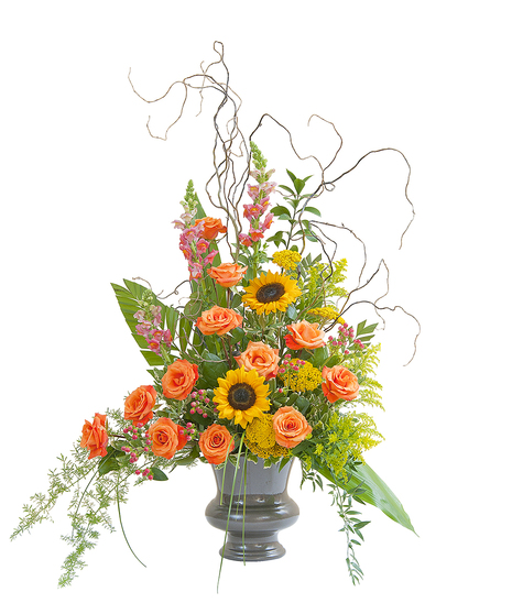 Sympathy arrangement of sunflowers, roses and more presented in an urn. 