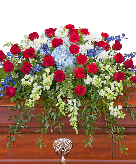 Patriotic casket spray of red, white and blue flowers with greenery. 