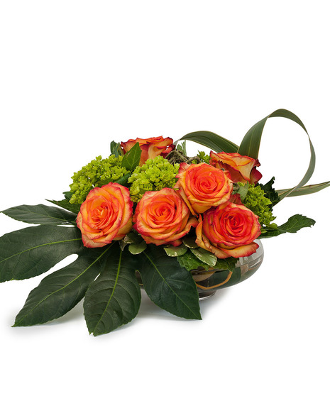 Orange roses and greenery in a contemporary vase. 