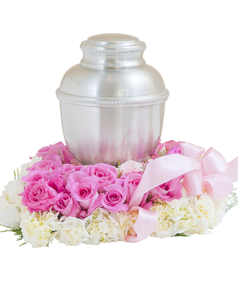 Urn surround of pink and white flowers with pink ribbon.