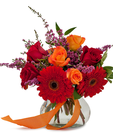 Red, orange and purple flowers in a glass vase.