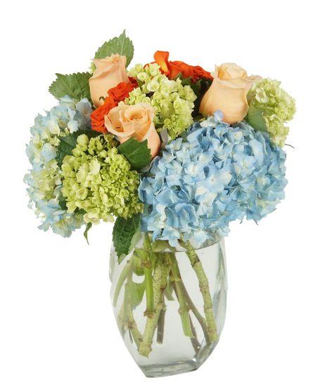 Light pink, orange and green flowers in a clear glass vase.
