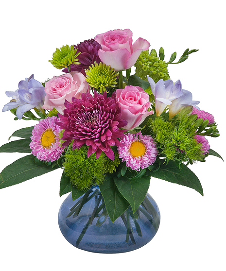 Mixed pastel flowers and greenery in a blue glass vase