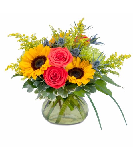 Sunflowers, roses and accent flowers in a clear glass vase.