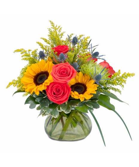 Sunflowers, roses and accent flowers in a clear glass vase.