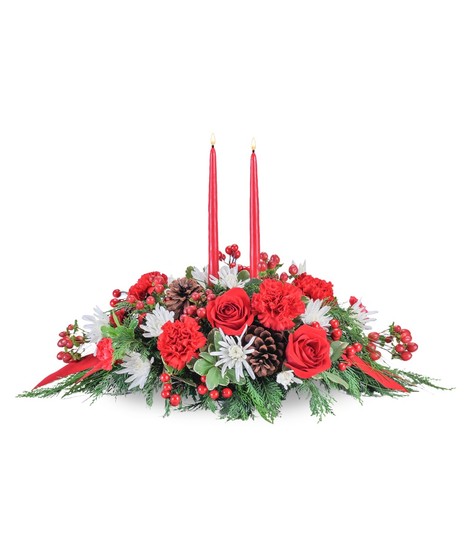Christmas centerpiece of evergreens, red carnations, white chrysanthemums and a taper candle.