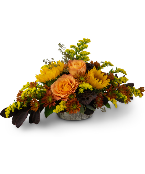 Autumn centerpiece with roses, sunflowers, solidago, mums and lotus pods in a weathered oak vase.