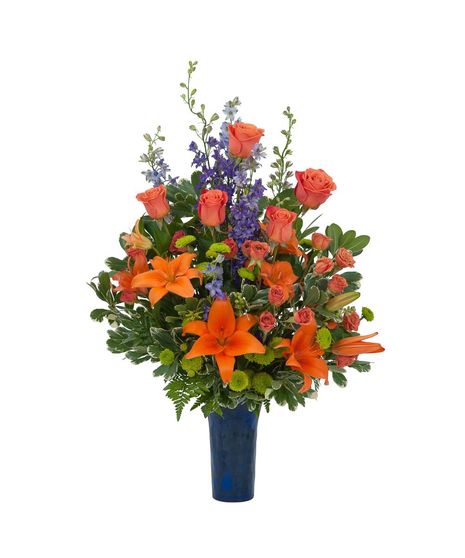 Lilies, roses, mums and larkspur in a cobalt blue bud vase.