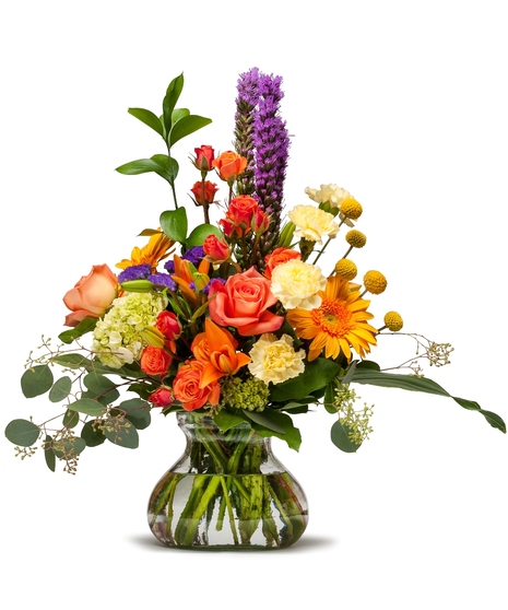 Bright fall flowers arranged in a clear vase.