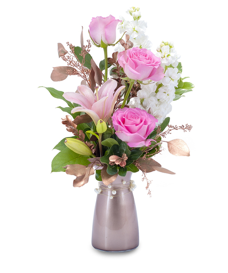 Pink roses and lilies with rose gold foliage in a rose gold vase.