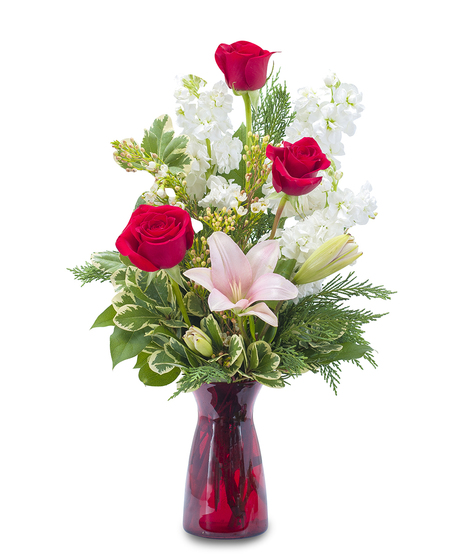 Lilies and roses with greenery in a red bud vase.